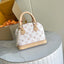 A Louis Vuitton Alma Mini handbag in white monogram canvas with beige leather trim and handles, resting on a white marble-topped table next to its cardboard packaging box.
