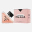 Prada Paradoxe Prada perfume bottle and packaging box on a light gray background. The bottle is triangular with a peach-pink liquid and a black cap, while the box is light pink with black text.