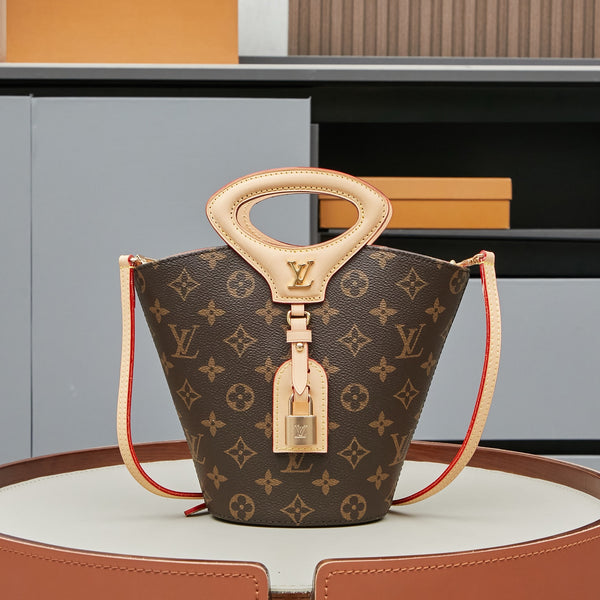 Louis Vuitton monogram canvas bucket bag with a top handle, lock detail, and red piping on the strap, displayed on a round pedestal.
