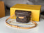 Louis Vuitton handbag with chain strap on a white surface with a yellow box in the background.