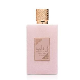 A rectangular pale pink perfume bottle with a textured metallic gold cap and a matching gold label featuring Arabic calligraphy, set against a plain white background.