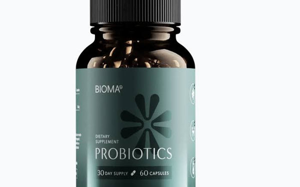 A bottle of BIOMA Probiotics dietary supplement, featuring a dark amber glass bottle with a black cap and a muted teal-green label, set against a plain white background.