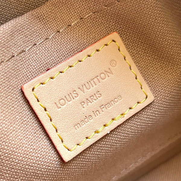 Close-up of a Louis Vuitton interior label stitched onto a beige canvas surface, with the embossed text 'LOUIS VUITTON PARIS made in France' visible.